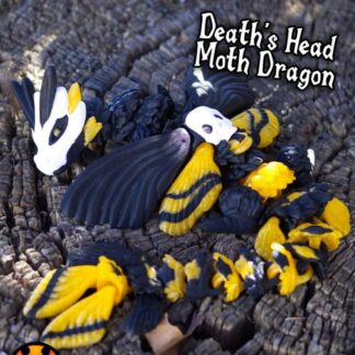 Black and yellow death’s-head moth dragon figurine resting on charred wood.